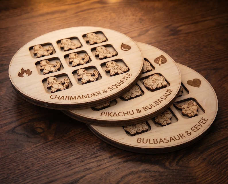 May include: Three circular wooden game boards featuring laser-engraved grid patterns and character icons. The boards are labelled with text including Charmander & Squirtle, Pikachu & Bulbasaur, and Bulbasaur & Eevee, with small fire, water, leaf, and heart symbols.