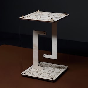 May include: A laser-cut wooden floating table with an intricate geometric design. The table has a square top and base, connected by a unique, open-frame support. The text "LASER CUT FILES" and "Floating table" are visible.