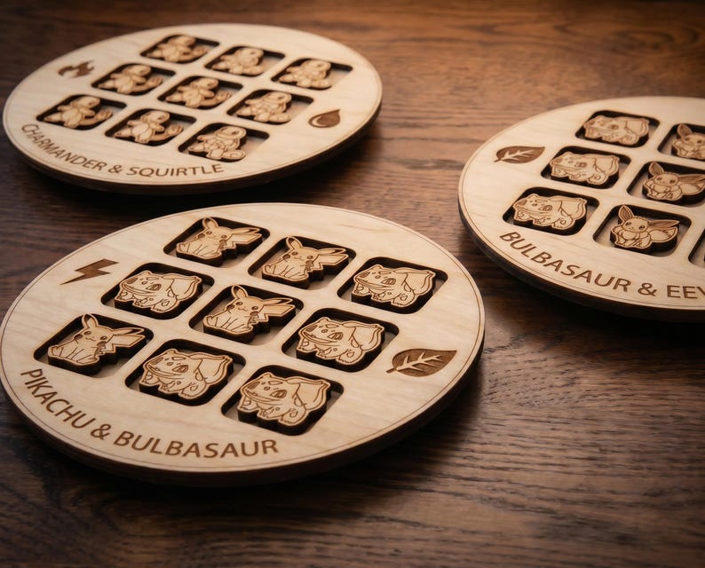 May include: Three circular light-coloured wooden game boards featuring laser-engraved character illustrations and text. The boards are labelled Charmander & Squirtle, Bulbasaur & Eevee, and Pikachu & Bulbasaur, with elemental icons like fire, water, and leaves.