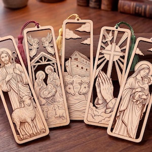 May include: Five rectangular wooden bookmarks featuring laser-cut religious scenes including the Good Shepherd, a nativity, Noah's ark, praying hands with a cross, and the Virgin Mary with child. Each bookmark has a colored tassel attached at the top.