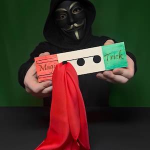 May include: A person wearing a black mask and hoodie holds a wooden prop with the words "Magic" and "Trick" on it, along with a red silk scarf. The text "Laser Cut Files" and "Tricks for kids and adults" are also visible.