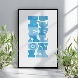 May include: A framed art print with the word "DEFINITION" in large, light blue, stylized letters. The print is in a black frame and is displayed against a white wall. The print also includes text at the bottom.