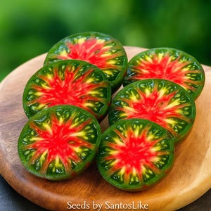 May include: Six halved heirloom tomatoes with vibrant red centers and green exteriors are arranged on a wooden cutting board. The tomatoes have a starburst pattern. The text "Seeds by SantosLike" is visible in the bottom right corner.
