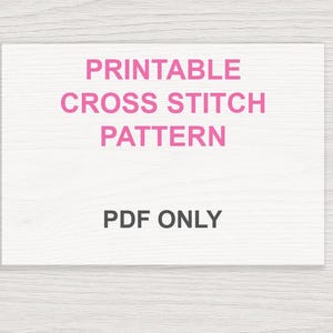 May include: A white rectangular card with the text "PRINTABLE CROSS STITCH PATTERN" in pink, and "PDF ONLY" in black. The background is a light wood grain pattern.