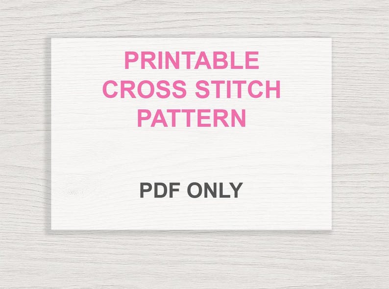 May include: A white rectangular card with the text "PRINTABLE CROSS STITCH PATTERN" in pink, and "PDF ONLY" in black. The background is a light wood grain pattern.
