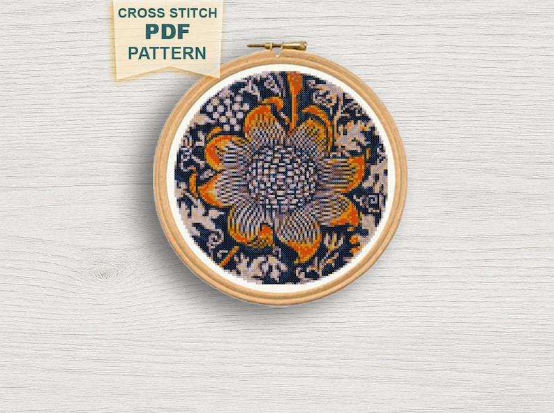 May include: A cross-stitch PDF pattern featuring a floral design in a wooden embroidery hoop. The design showcases a large, stylized flower with orange and white petals against a dark blue background. The text "CROSS STITCH PDF PATTERN" is visible.