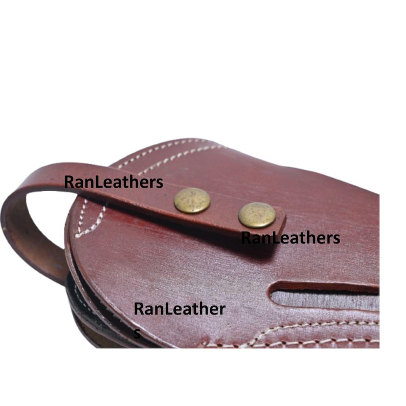 Może przedstawiać: Zbliżenie brązowej sk&oacute;rzanej sakiewki z uchwytem i ćwiekami w kolorze mosiądzu. Widoczny jest tekst "RanLeathers". Sakiewka ma białe szwy na krawędziach.