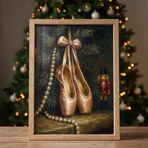 May include: A framed painting depicts a pair of pink ballet pointe shoes hanging from a bow, with a pearl necklace draped nearby. A toy nutcracker stands to the right. The background features a Christmas tree.