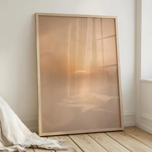 May include: A framed art print with a warm, muted colour palette. The image shows a bed with pillows, a window with curtains, and a sunrise or sunset. The frame is a light wood colour.