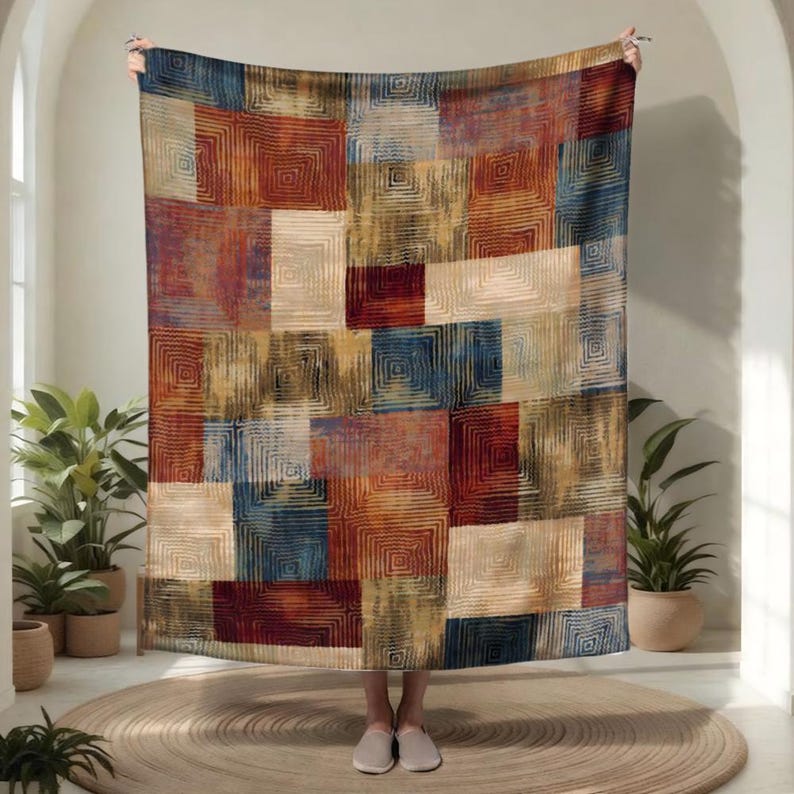 Peut inclure: Un plaid rectangulaire pr&eacute;sentant un motif patchwork de carr&eacute;s et de rectangles dans des tons rouge profond, bleu marine et cr&egrave;me. Chaque bloc contient un motif de carr&eacute;s concentriques avec des lignes fines et textur&eacute;es sur le tissu.