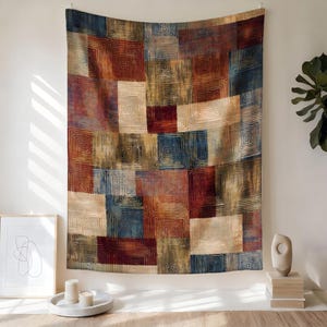 Peut inclure: Une tapisserie murale rectangulaire pr&eacute;sentant un motif en patchwork de carr&eacute;s et de rectangles. Le design se compose de lignes carr&eacute;es concentriques dans des tons de rouge profond, bleu marine, cr&egrave;me et vert olive, cr&eacute;ant un aspect textur&eacute;.