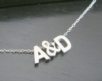 Può includere: Una collana d'argento con un ciondolo che dice "A&D".