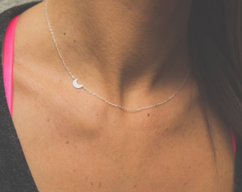 May include: A silver necklace with a crescent moon pendant. The necklace is delicate and simple, and would make a great gift for a friend or loved one.