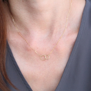 May include: A gold chain necklace with two interlocking circles as a pendant.