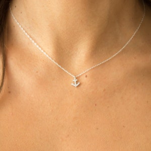 May include: A delicate silver chain necklace with a small, sparkling anchor pendant.