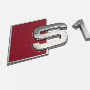 Peut inclure: Emblème S1 chromé avec fond rouge. L'emblème présente un "S" chromé et un "1" chromé séparé. Le fond rouge est en forme de losange avec une bordure chromée. Emblème automobile.