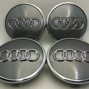 Peut inclure: Quatre enjoliveurs de roue de voiture gris et argent. Chaque capuchon présente le logo Audi, un ensemble de quatre anneaux entrelacés, dans une finition argentée. Les capuchons ont un fond gris métallique et une bordure argentée.