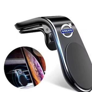 May include: Black car phone mount with silver trim and the Volvo logo. The mount attaches to an air vent and has a magnetic surface to hold a phone. A circular inset shows the phone in use.