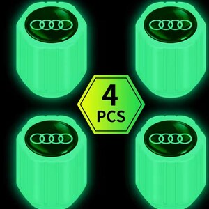 May include: Four glowing green tire valve stem caps with the Audi logo on a black background. A green and yellow hexagon displays the text "4 PCS". The caps have a cylindrical shape and a dark green top.