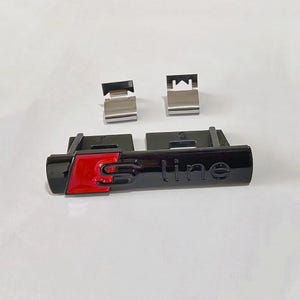 Peut inclure: Emblème S line noir et rouge avec deux clips argentés. L'emblème a une finition brillante et le texte "S line" est visible. Le fond est une surface blanche unie.