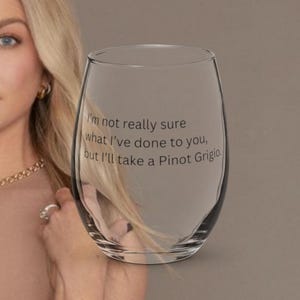 May include: A clear stemless wine glass with the text "I'm not really sure what I've done to you, but I'll take a Pinot Grigio." The glass is oval-shaped and sits on a neutral background.
