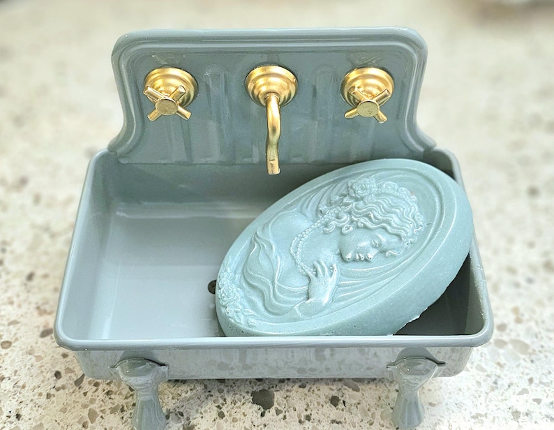 Grey Blue Farmhouse Sink Fish with gold faucet and knobs. Blue cameo soap is sitting in dish.