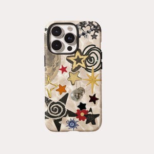 May include: A phone case featuring a cream-coloured backdrop adorned with a collage of celestial and disco-themed motifs. The design incorporates gold, black, and red stars, a miniature disco ball, and a sun graphic. The case has a black camera ring.