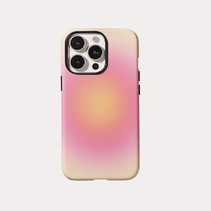 Puede incluir: Funda de teléfono con un diseño degradado. La funda pasa de un beige claro en la parte superior a un rosa suave en el centro, con un centro amarillo cálido. Las lentes de la cámara del teléfono son visibles.