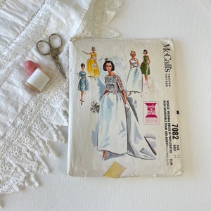 Puede incluir: Patrón de costura vintage McCall's para un vestido de novia en dos longitudes con una cola desmontable y una chaqueta. El número de patrón es 7082, talla 12, busto 81 cm y cuesta 1,00 €.