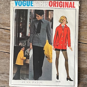 May include: Vogue Paris Original sewing pattern number 2575 by Jean Patou. The pattern features two models wearing different outfits. One model is wearing a gray jacket with a black tie and black pants. The other model is wearing a red jacket with black shorts and black tights.