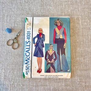 May include: A vintage McCall's sewing pattern, number 4931, featuring illustrations of a blazer, vest, skirt, and pants. The pattern includes a size 8 with a bust measurement of 31.5 inches. A thimble and scissors are also in the image.