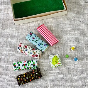 Op de afbeelding: Assortiment van stofresten met bloemen- en geometrische patronen in rood, blauw en wit. Er zijn ook spoelen garen en een naaldenkussen met spelden.