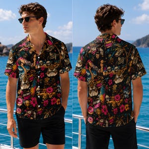 May include: A short-sleeve button-down shirt with a black base featuring a colorful graphic print of skulls, donuts, surfboards, and tropical flowers. The text "SURF HARD" and "GOOD DAMN IT DONUT!" is printed in pink and yellow across the fabric.