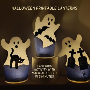 May include: Three Halloween-themed lanterns with ghost and bat cutouts. The lanterns are white with a blue base and are illuminated from within. Text at the top reads "HALLOWEEN PRINTABLE LANTERNS". The middle lantern sits on a wooden base with text that reads "EASY KIDS ACTIVITY WITH MAGICAL EFFECT IN 5 MINUTES".