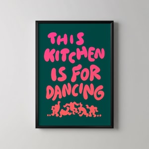 May include: Framed art print with the text "THIS KITCHEN IS FOR DANCING" in bright pink on a dark teal background. The bottom of the print features a line of stylized dancing figures in the same pink color. The frame is black.