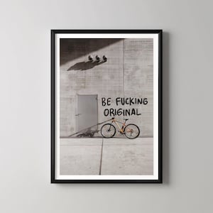 May include: Framed print showing a mountain bike against a concrete wall with the words "BE FUCKING ORIGINAL" spray-painted in black. The bike is orange and yellow.