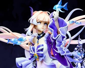 May include: A detailed figurine of a character with light pink and white hair, wearing a flowing purple and white dress. The figure is adorned with blue accents and fish-shaped ornaments. The overall design has a fantasy theme.