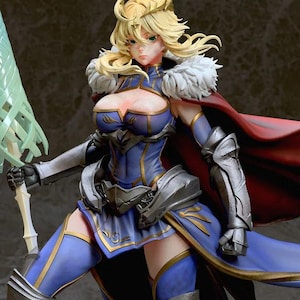 Puede incluir: Figura detallada de una guerrera con un atuendo azul y dorado, con armadura plateada y una capa roja. Tiene cabello rubio, una corona y sostiene una espada verde. La figura tiene una expresión decidida.