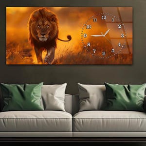 May include: A rectangular wall clock featuring a majestic lion walking towards the viewer, set against a warm, golden sunset backdrop. The clock face is integrated into the design, with silver numerals and hands. The artwork is displayed above a gray sofa with green and white pillows.