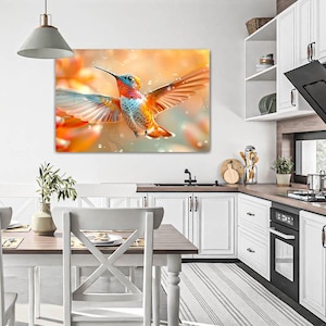 Puede incluir: Una vibrante impresión en lienzo de un colibrí en vuelo, mostrando un espectro de colores que incluye naranja, azul y rojo. Las alas del ave están extendidas, sobre un fondo suave y borroso. La obra de arte se exhibe en un entorno de cocina moderna.