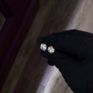 May include: Two round, sparkling diamond stud earrings. The earrings are held by a gloved hand, showcasing their brilliance. The diamonds reflect light, creating a dazzling display. A classic jewelry item.