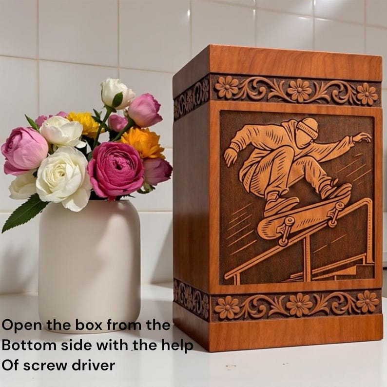 Wooden memorial urn box for ashes with skateboard engraved artwork, floral carved borders, polished natural wood texture, standing on shelf near candle and flowers, ideal for remembrance and tribute.