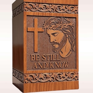 Personalized wooden urn box with engraved name, birth and passing dates, and short message under the quote “Be Still and Know.” Customizable Christian urn with cross and Jesus design, handmade with care for a unique and heartfelt tribute. Laser engraving adds a personal, lasting touch for your loved one’s memory.