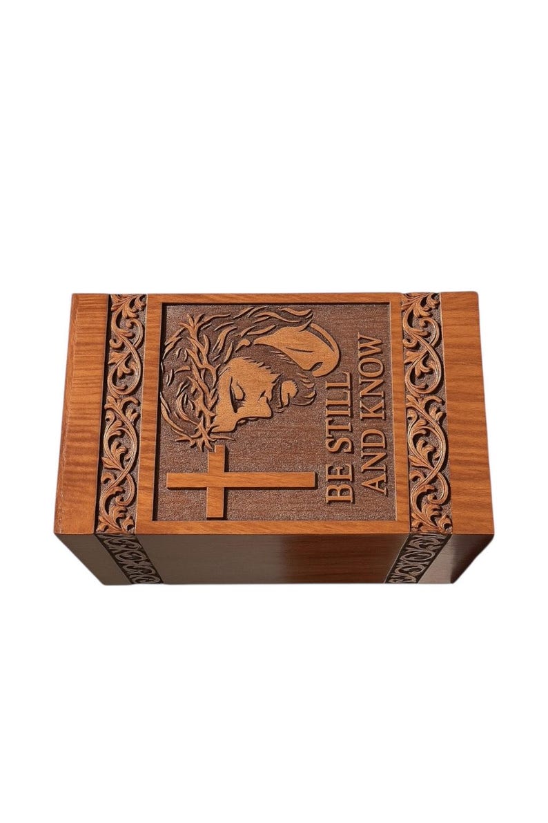 Elegant handcrafted wooden urn box engraved with the image of Jesus and a cross, featuring the words “Be Still and Know.” Made from solid wood with detailed carved floral borders and smooth finish. A beautiful Christian memorial urn for adult ashes, symbolizing peace, love, and eternal faith. Perfect for home remembrance or funeral service display.