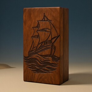 Memorial wooden urn box with detailed sailboat engraving, handcrafted for elegance and durability. The natural wood grain and artistic ship carving create a peaceful tribute. Custom engraving available for personalization, making it a unique remembrance gift.