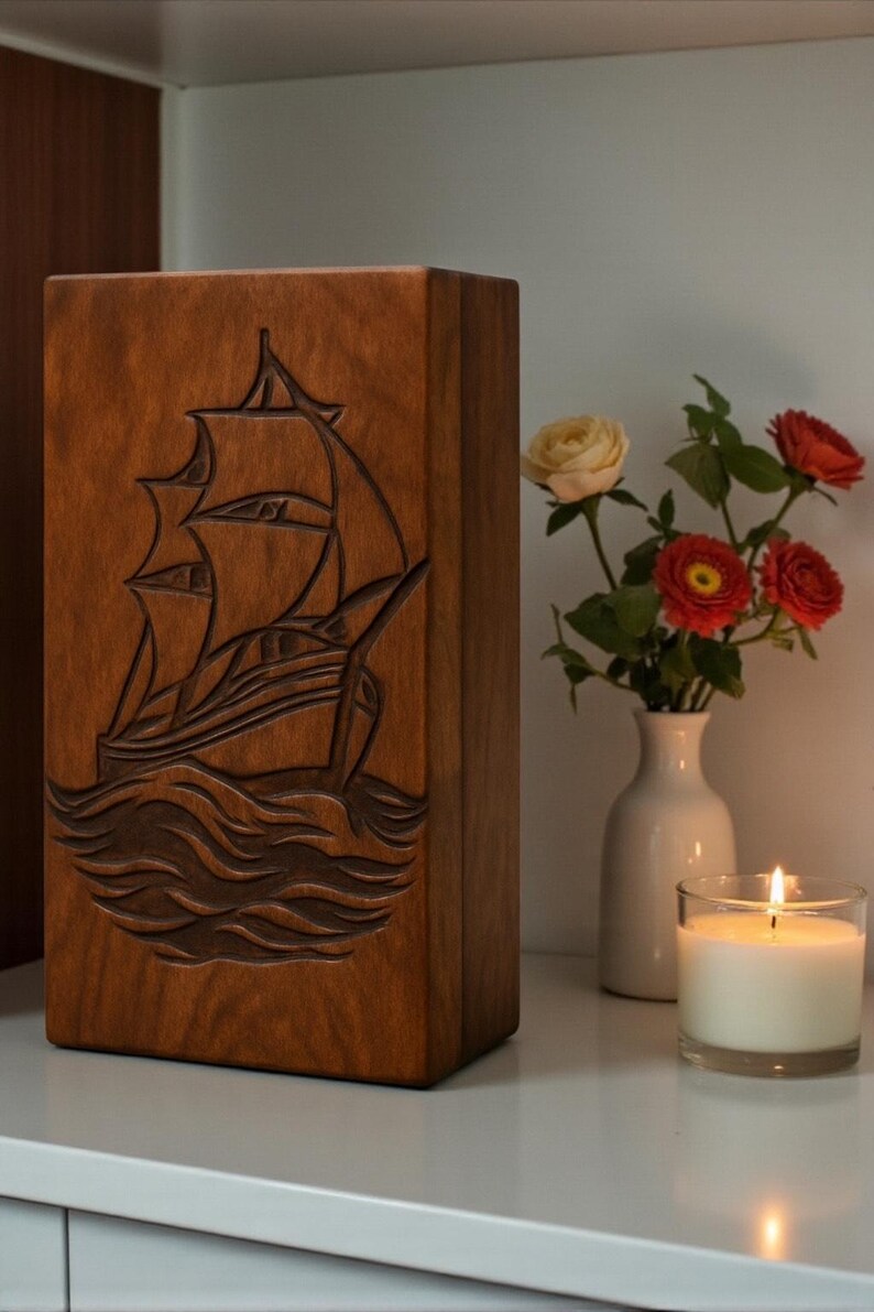 Beautifully engraved wooden urn box with a nautical sailboat design. The smooth finish and deep carving make it an ideal memorial keepsake. Designed to securely hold ashes and customizable with personal details to create a heartfelt tribute.