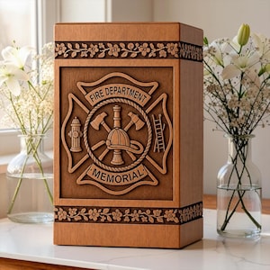 Pode incluir: Uma urna memorial retangular de madeira com um emblema de corpo de bombeiros esculpido na frente. O emblema exibe um capacete de bombeiro, machados cruzados, uma escada e um hidrante. O texto FIRE DEPARTMENT e MEMORIAL está esculpido no design.