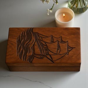 Hand-engraved wooden urn box with a beautiful sailboat design, representing peace and eternal journey. Crafted from solid wood with a polished natural finish. Ideal for memorial services, home tribute displays, and personalized engraving for names and dates.