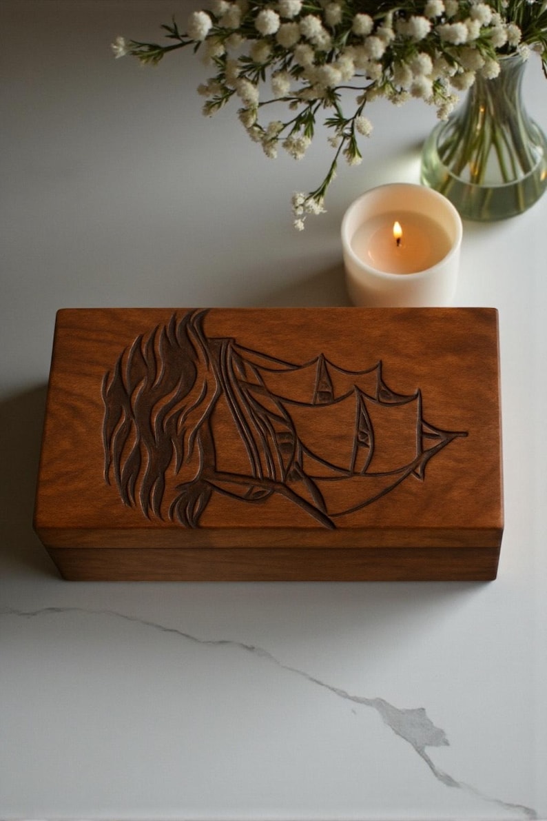 Hand-engraved wooden urn box with a beautiful sailboat design, representing peace and eternal journey. Crafted from solid wood with a polished natural finish. Ideal for memorial services, home tribute displays, and personalized engraving for names and dates.