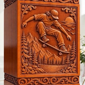 May include: A rectangular wooden box featuring a detailed relief carving of a person skateboarding in front of a mountain landscape with pine trees, a lake, and a sun. The border is decorated with ornate scrollwork patterns on all sides.